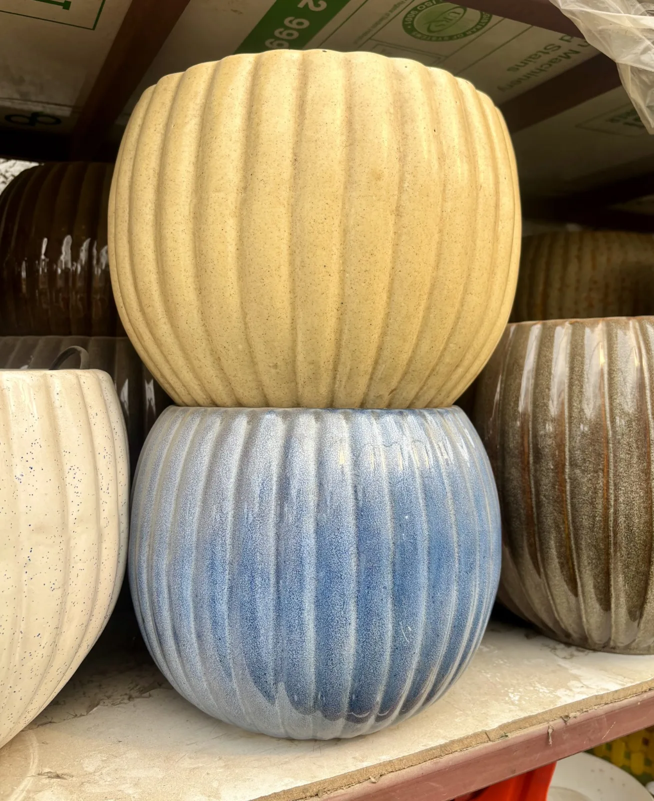 A stack of two decorative ceramic planters is displayed on a shelf